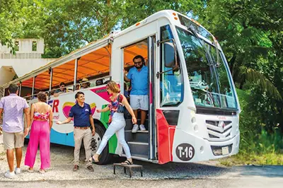 Open-top Cozumel bus boarding tourists